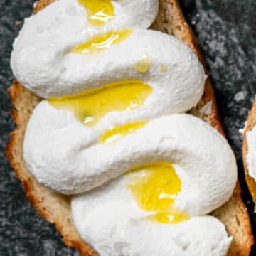 slice of whipped ricotta toast drizzled in olive oil on a grey plate