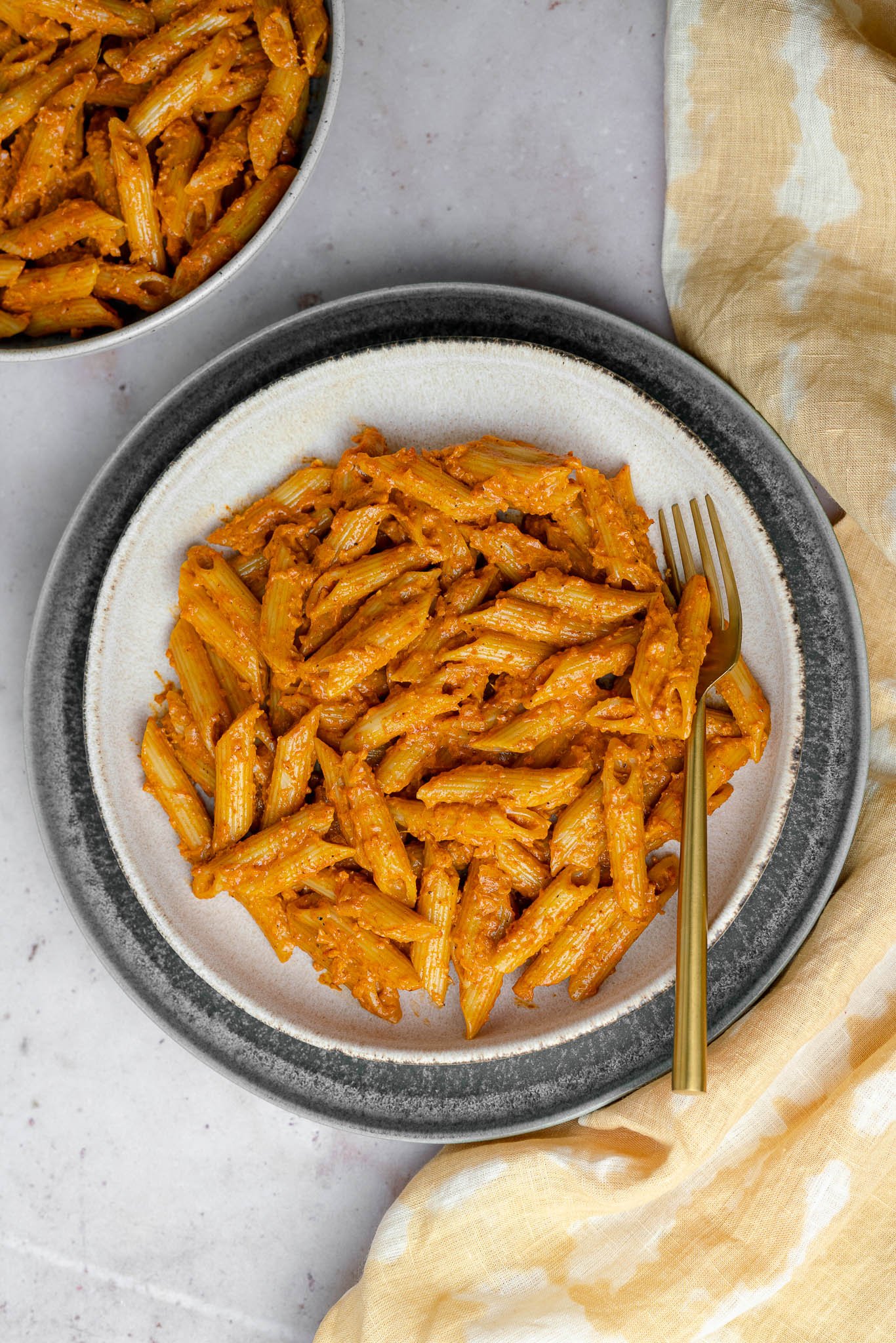 butter masala pasta in a pasta bowl with a golden fork