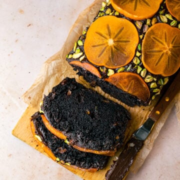 Persimmon Chocolate Loaf Cake with persimmon slices and pistachios in a pinch bowl