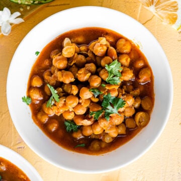 chole in a white bowl with lemon wedges