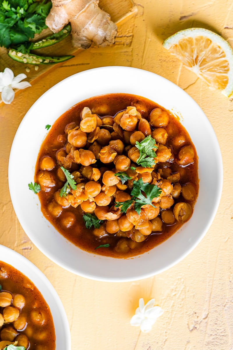 chole in a white bowl with lemon wedges