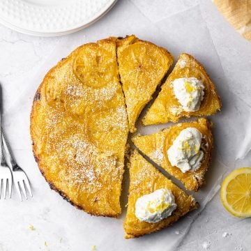 lemon cardamom olive oil cake sliced into four pieces. three of them have whipped cream and lemon zest