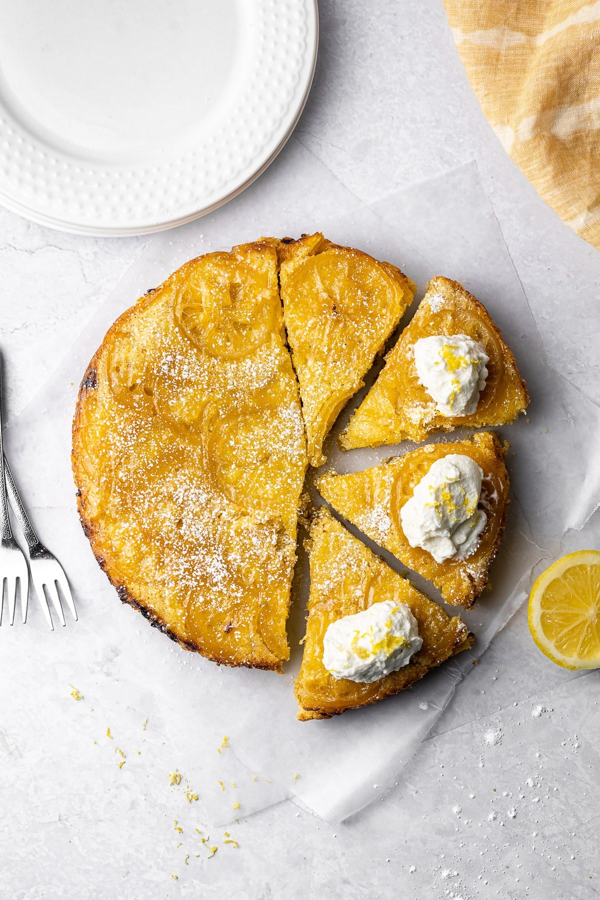 lemon cardamom olive oil cake sliced into four pieces. three of them have whipped cream and lemon zest