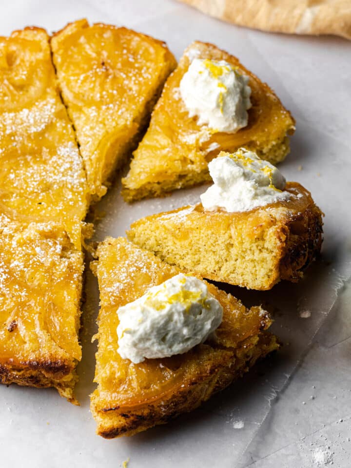 sliced lemon cardamom olive oil cake with a slice perched upwards to show moist cake
