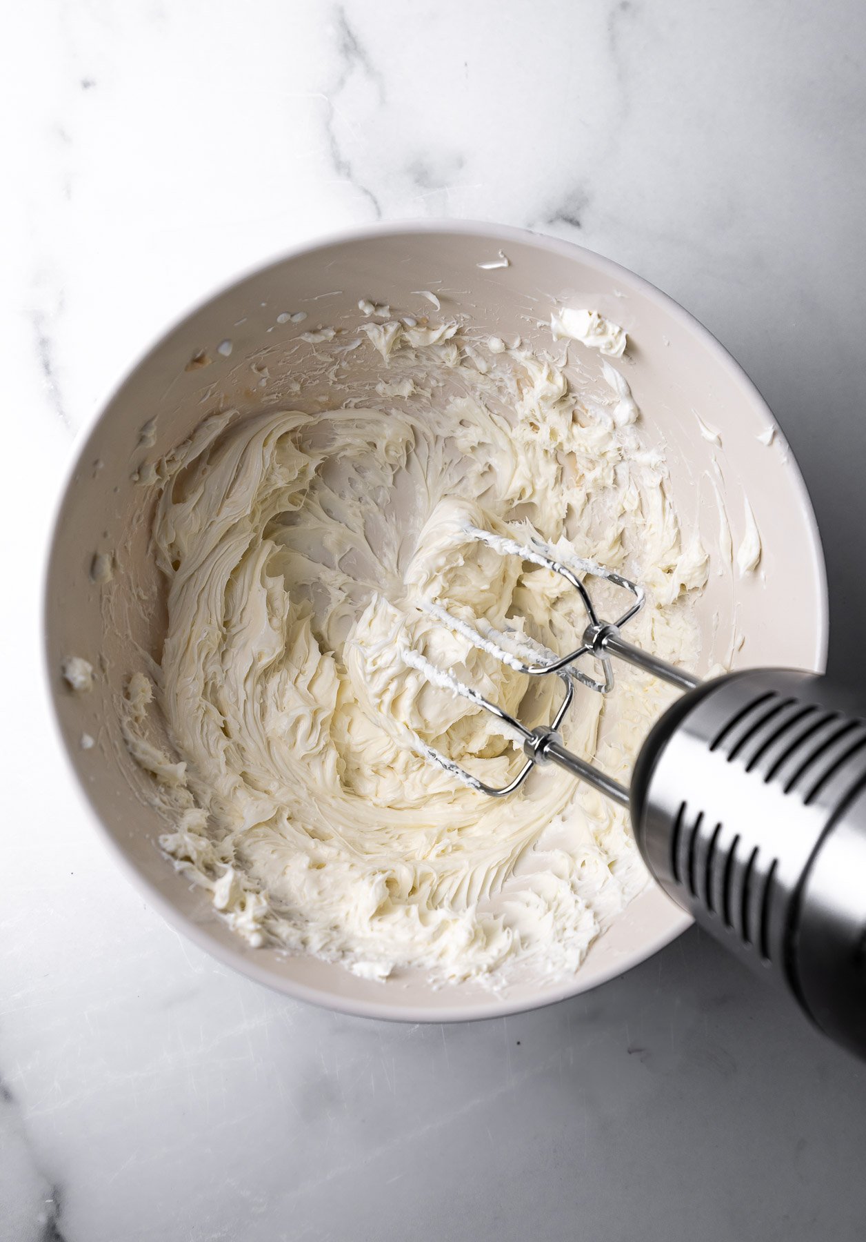 No Bake Cheesecake Filling being mixed with a handheld mixer in a bowl