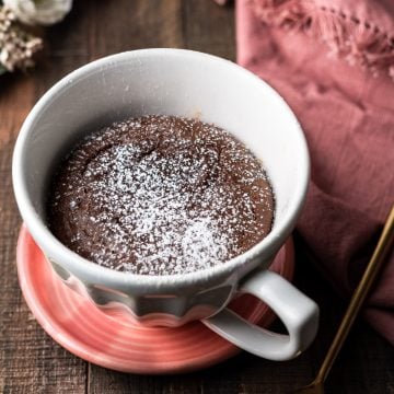 Nutella Lava Mug Cake in a mug on a plate with a spoon