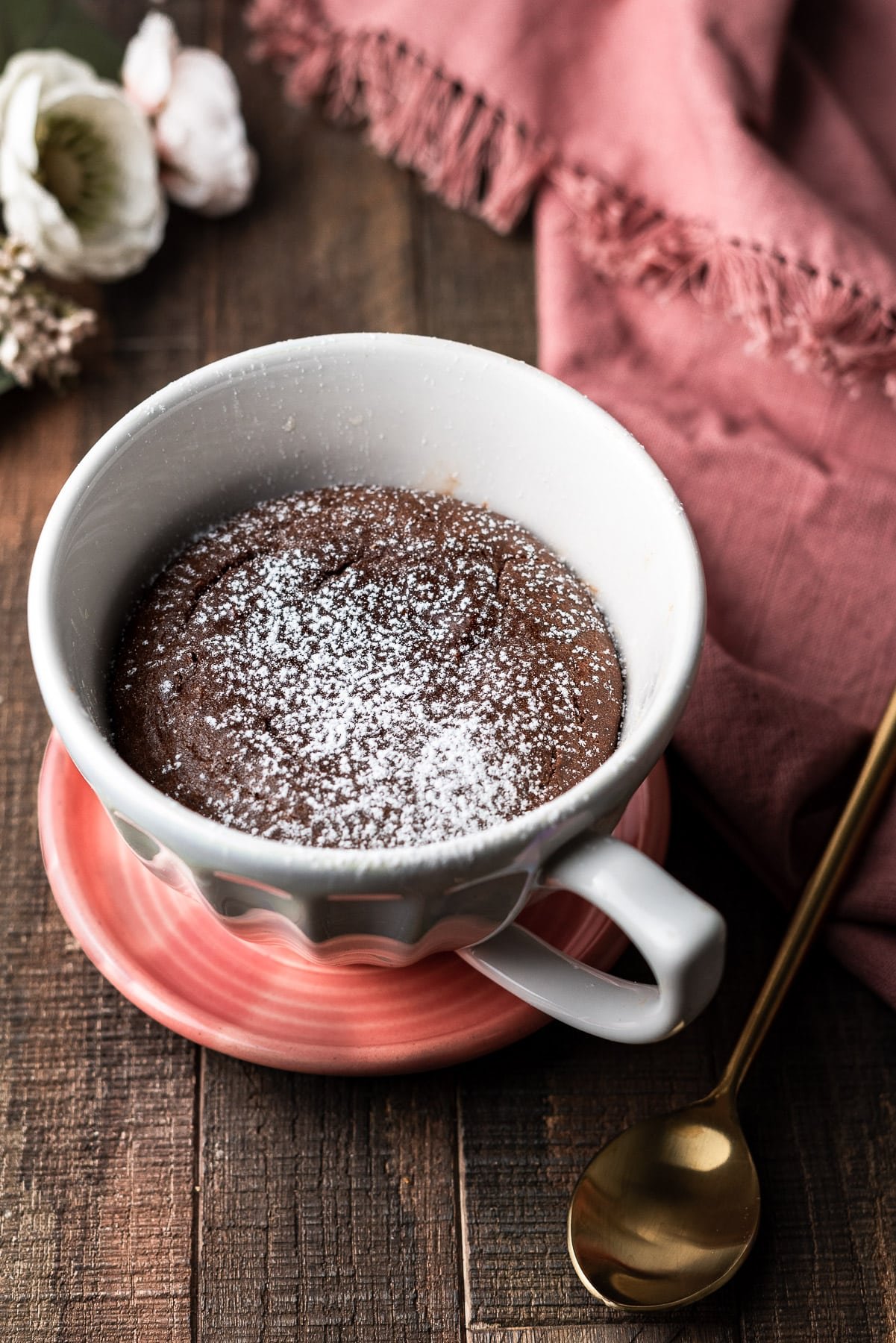 Nutella Lava Mug Cake in a mug on a plate with a spoon