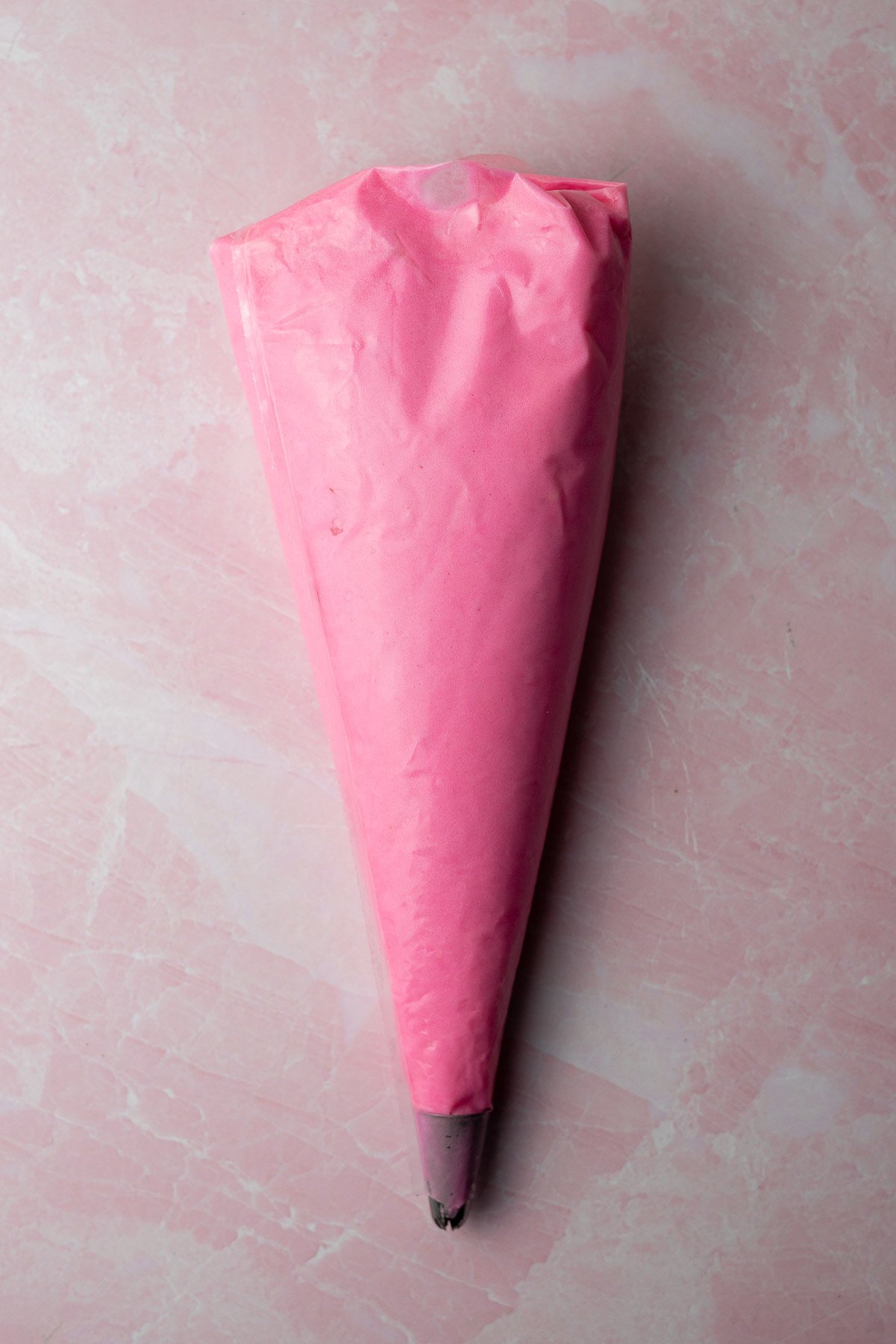 decorating bag of pink buttercream frosting with a star tip