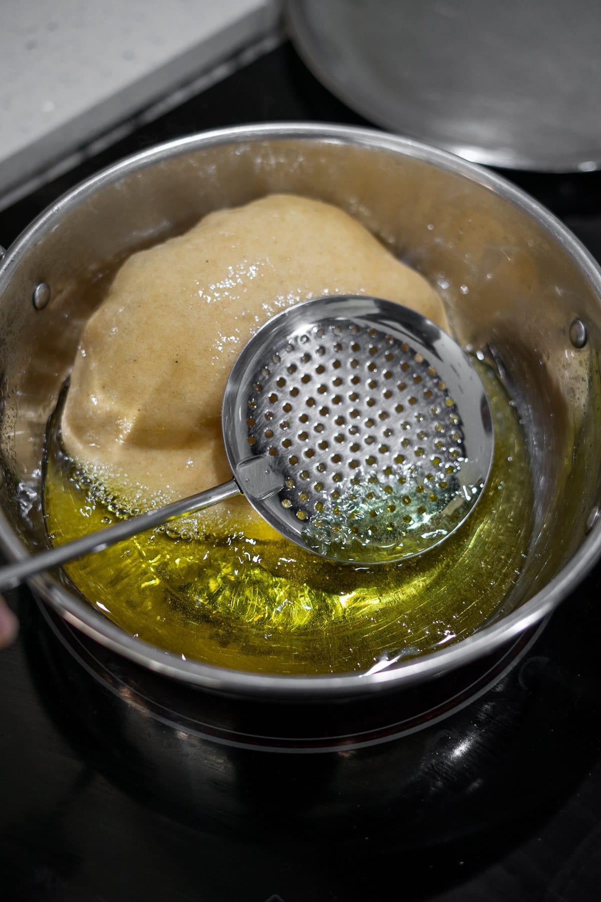 bhatura being fried in oil and beginning to puff