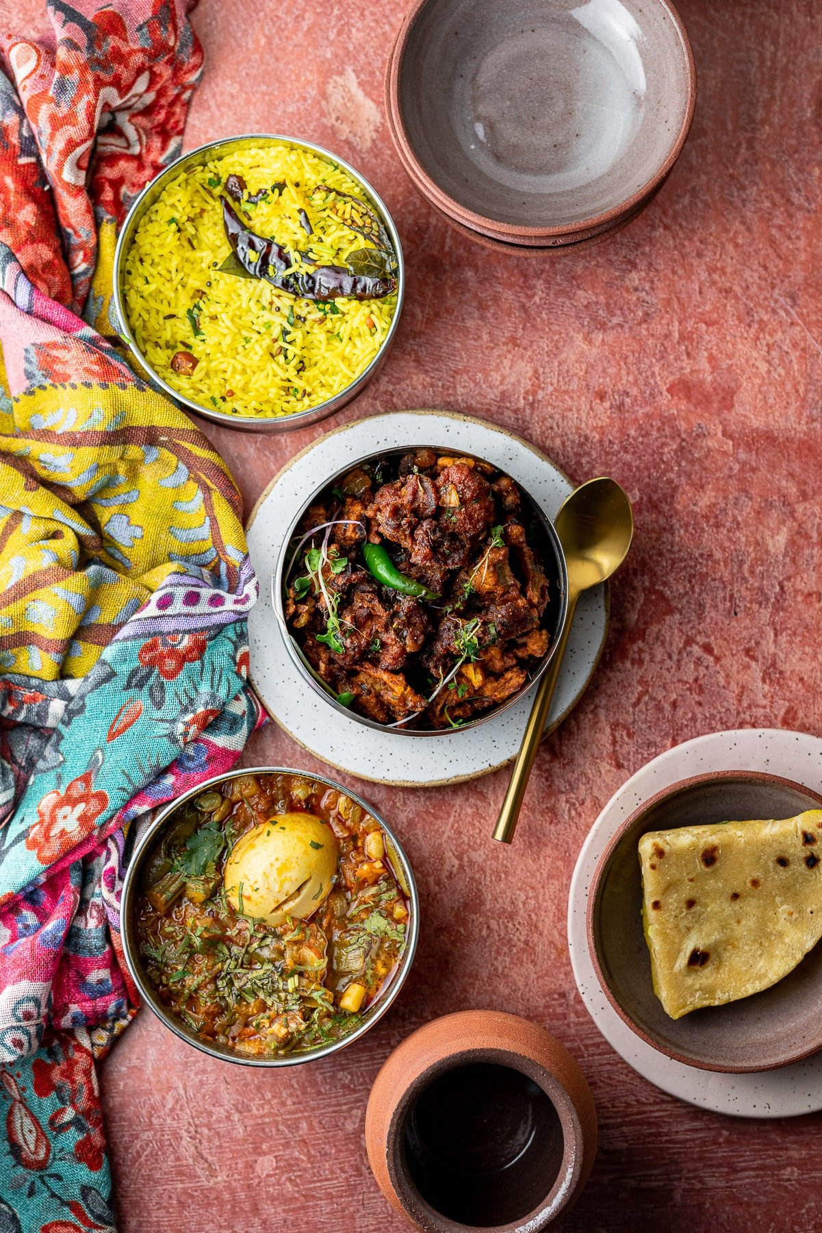 a spread of indian food with rice, roti, chicken, and egg curry