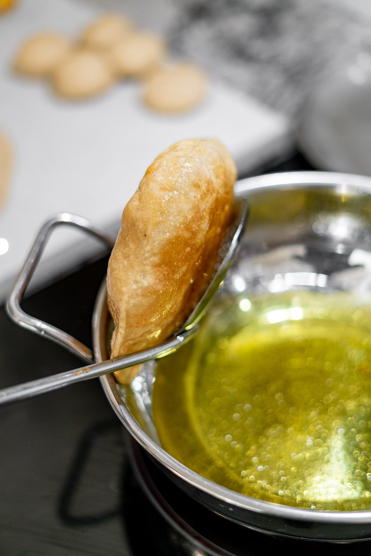 Using a slotted spoon to remove bhature from oil