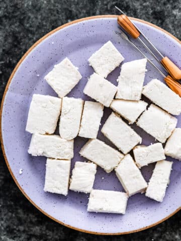 homemade paneer cut up in rectangles on a plate with appetizer picks