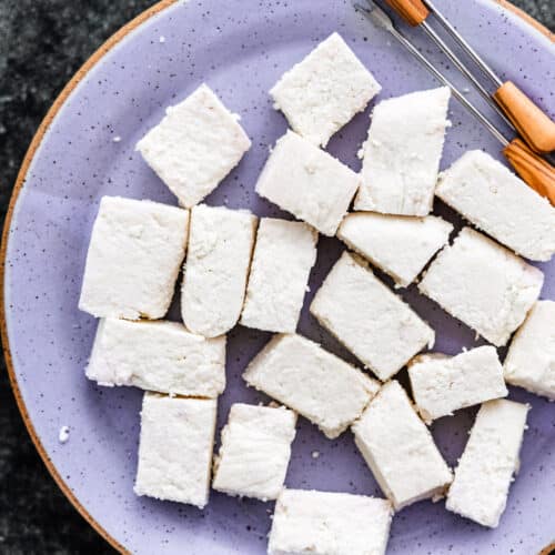 homemade paneer cut up in rectangles on a plate with appetizer picks
