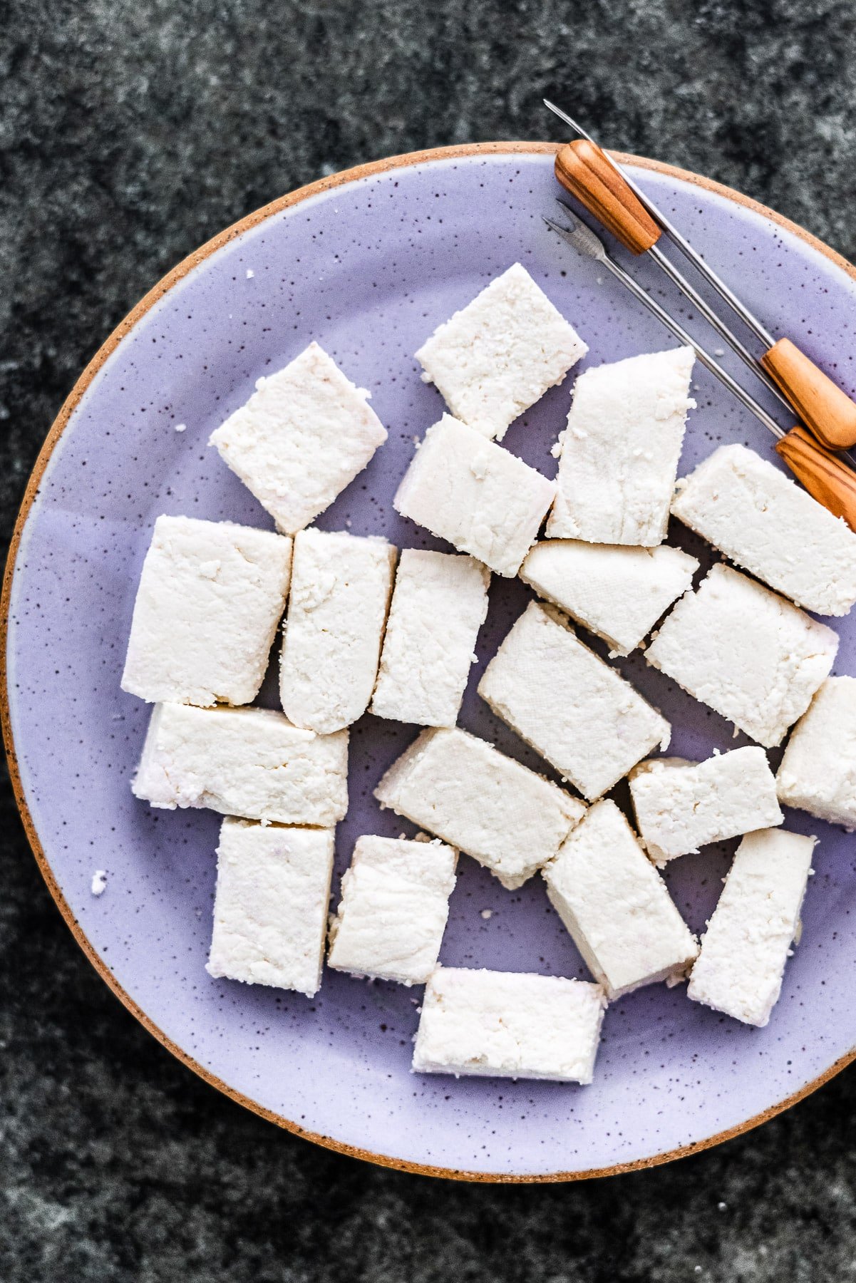 homemade paneer cut up in rectangles on a plate with appetizer picks