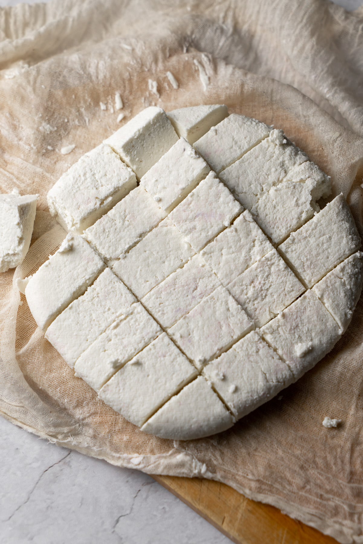 a cut block of paneer over a cheese cloth