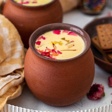 two cups of thandai in chai cups on a white tray