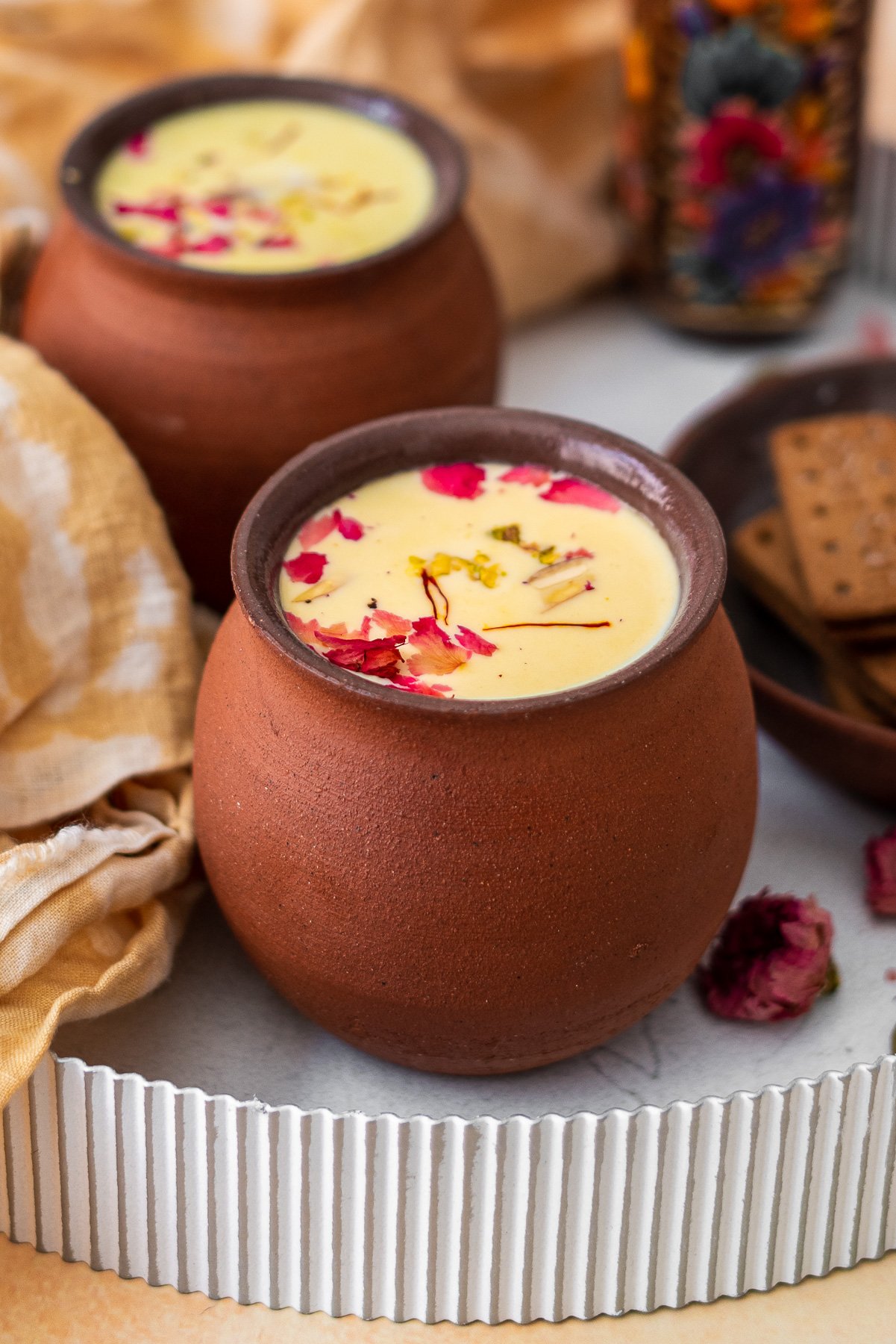 two cups of thandai in chai cups on a white tray