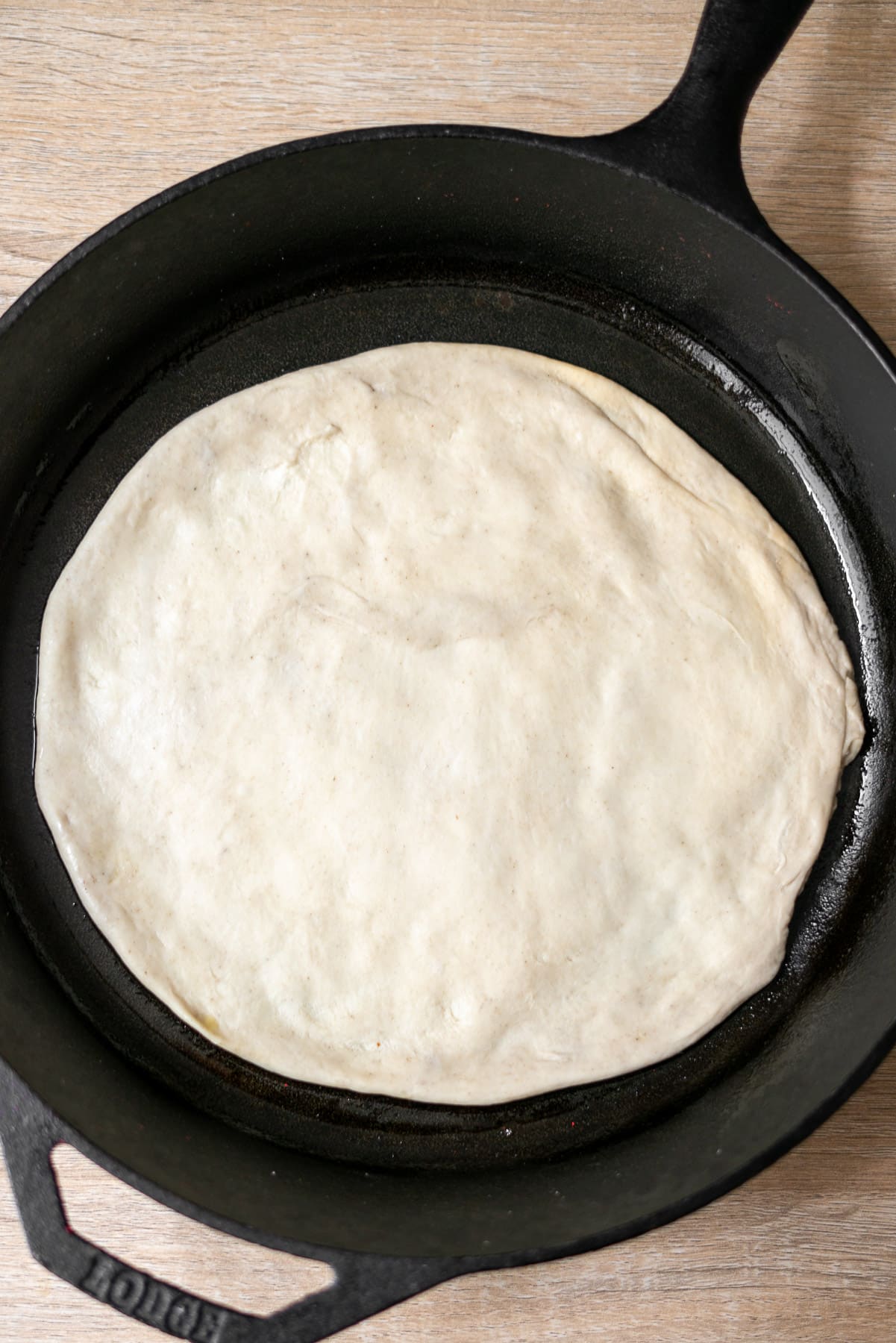 unbaked pizza dough shaped in a lodge cast iron pan