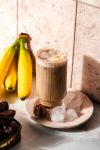 Banana Date Latte on a plate with ice surrounded by bananas and dates.