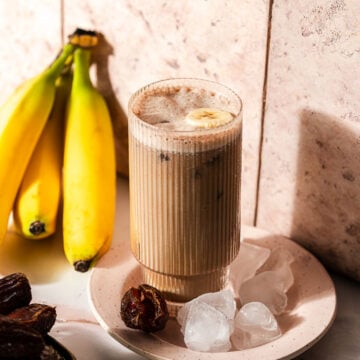 Banana Date Latte on a plate with ice surrounded by bananas and dates.