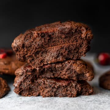 stack of brownie cookies with cherries in the background
