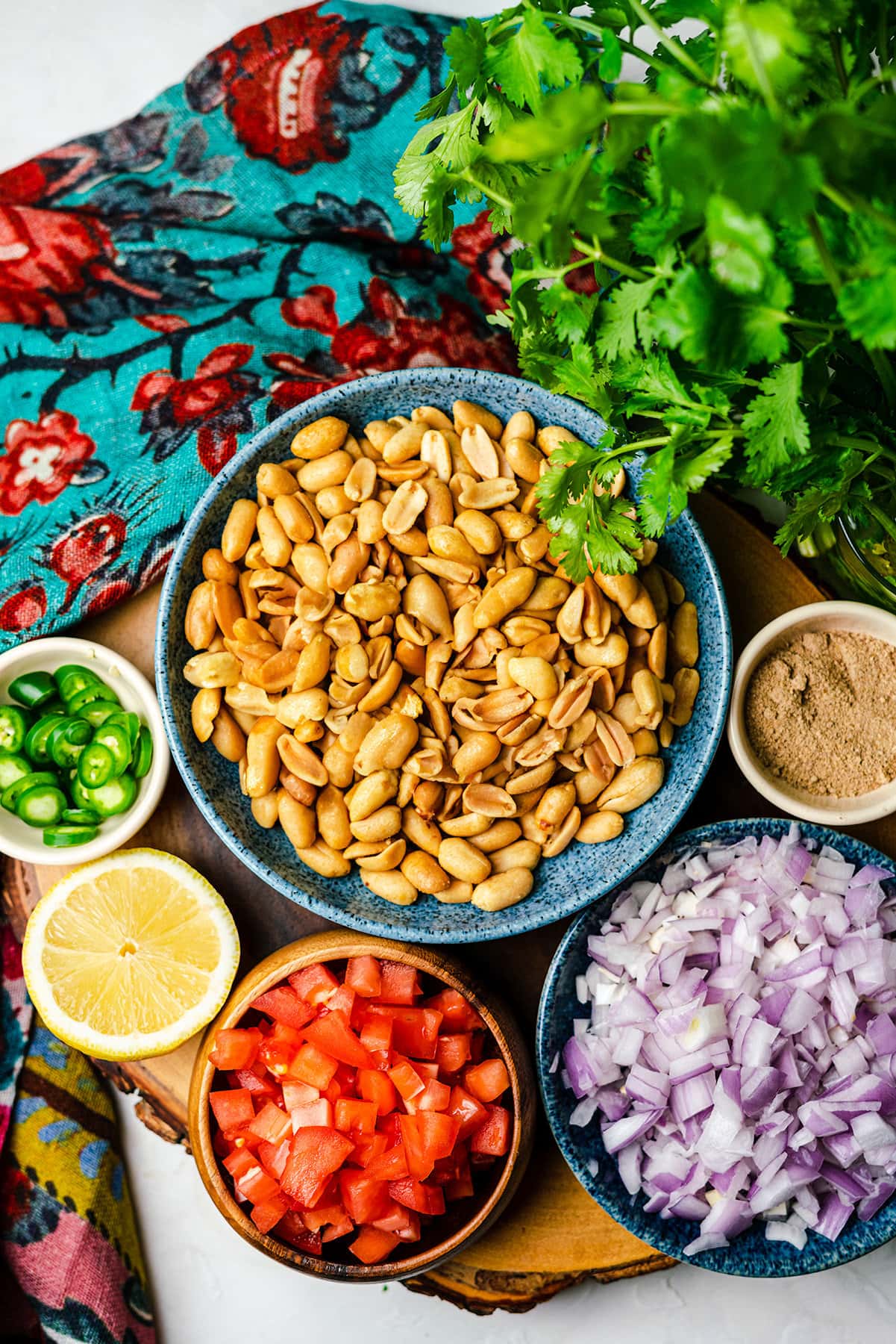 Peanut chaat ingredients with peanuts, onions, chaat masala, tomatos, lemons, and serrano peppers.