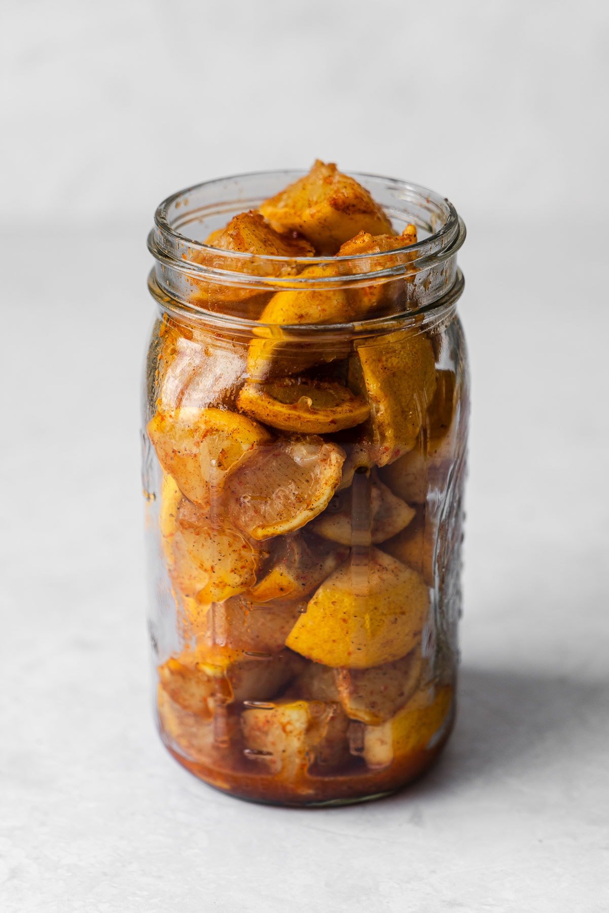 Lemons coated in spices in a mason jar.