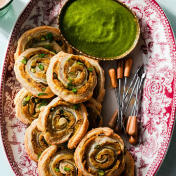 Samosa Pinwheels on a platter with appetizer picks and cilantro green chutney.