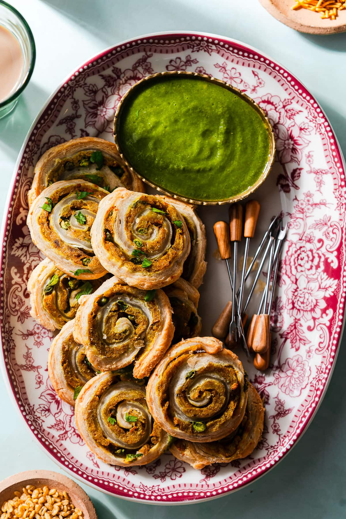 Samosa Pinwheels on a platter with appetizer picks and cilantro green chutney.