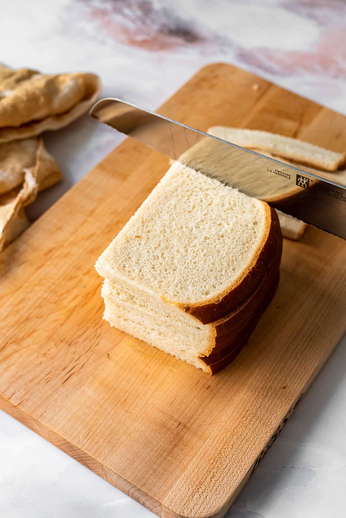 stack of white bread being sliced with a zwilling bread knife