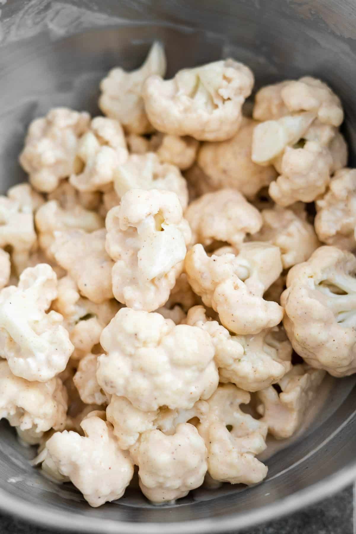 cauliflower florets covered in a spiced batter in a metal bowl