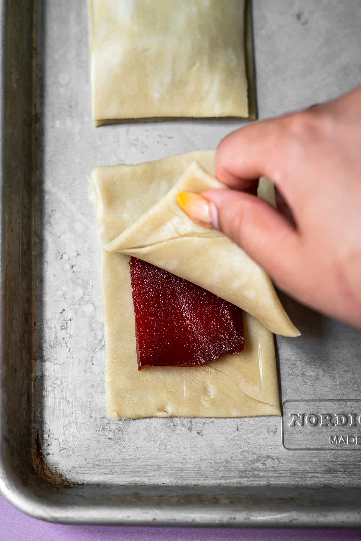 adding the top layer of the pie crust on top of the pop tart filled with guava glaze