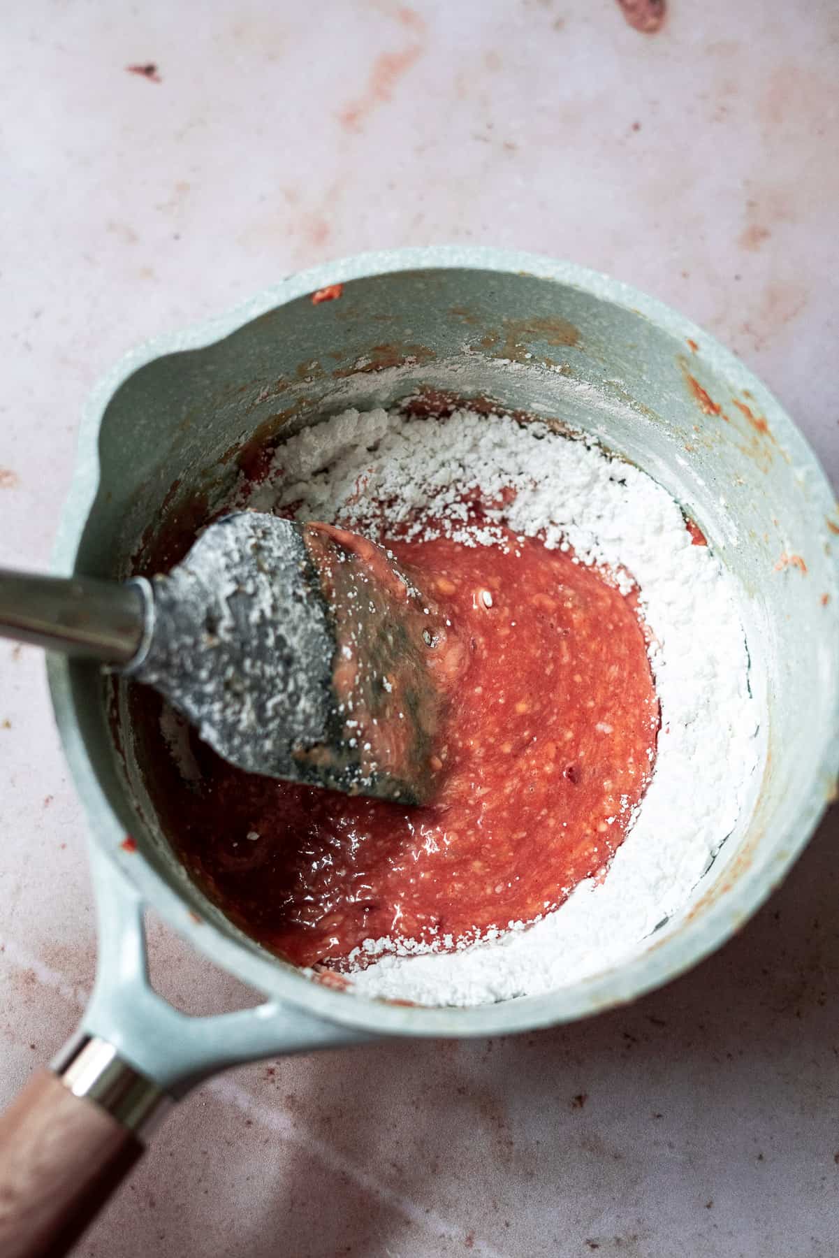 mixing together the powdered sugar with the guava cheese glaze in a sauce pan with a spatula