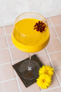 Mango Lassi with a marigold in a spritz glass on a coaster