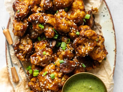 cauliflower wings in a platter with appetizer picks and a condiment bowl of mint-cilantro chutney and fresh tamarind.