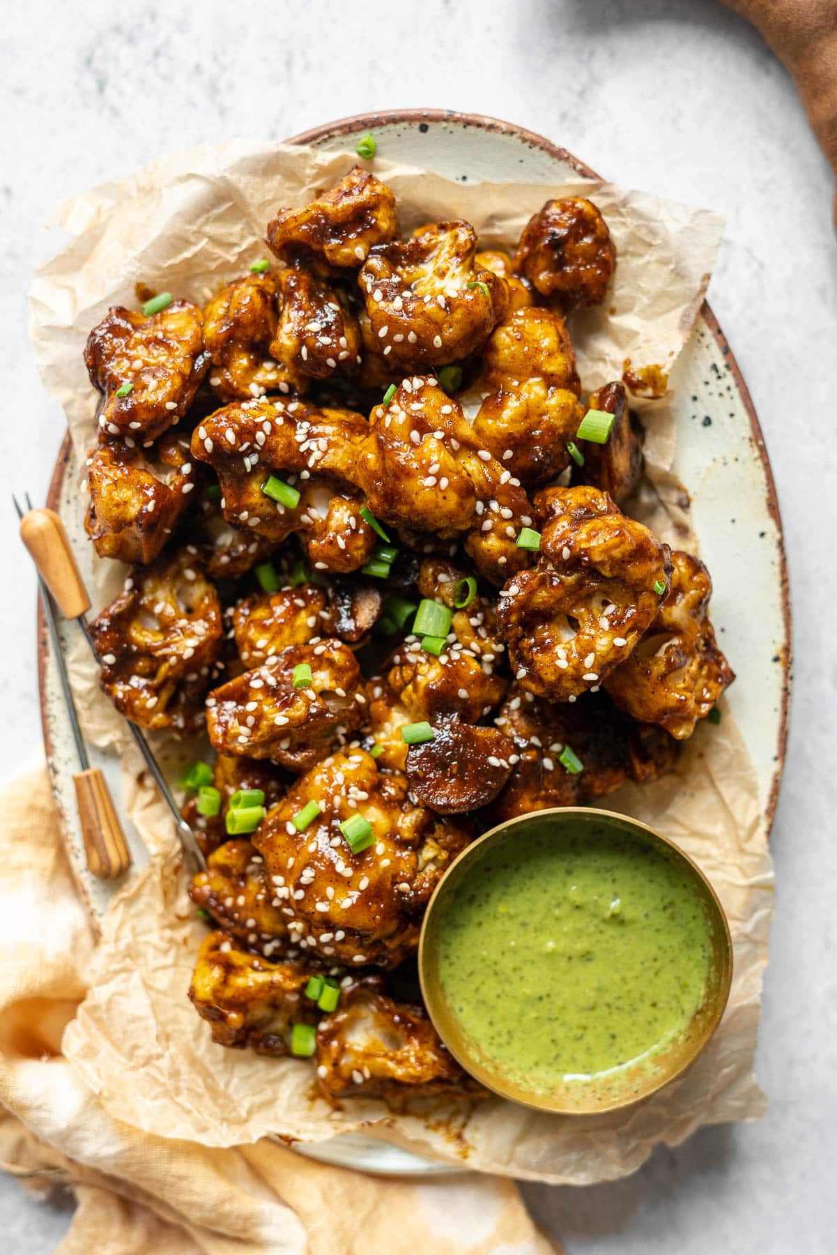 cauliflower wings in a platter with appetizer picks and a condiment bowl of mint-cilantro chutney and fresh tamarind.