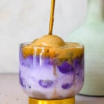 a gold spoon stirring instant espresso with ube and coconut milk