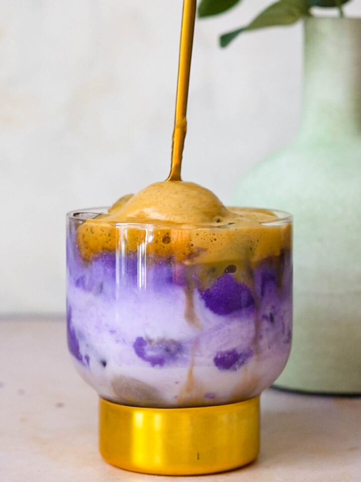 a gold spoon stirring instant espresso with ube and coconut milk