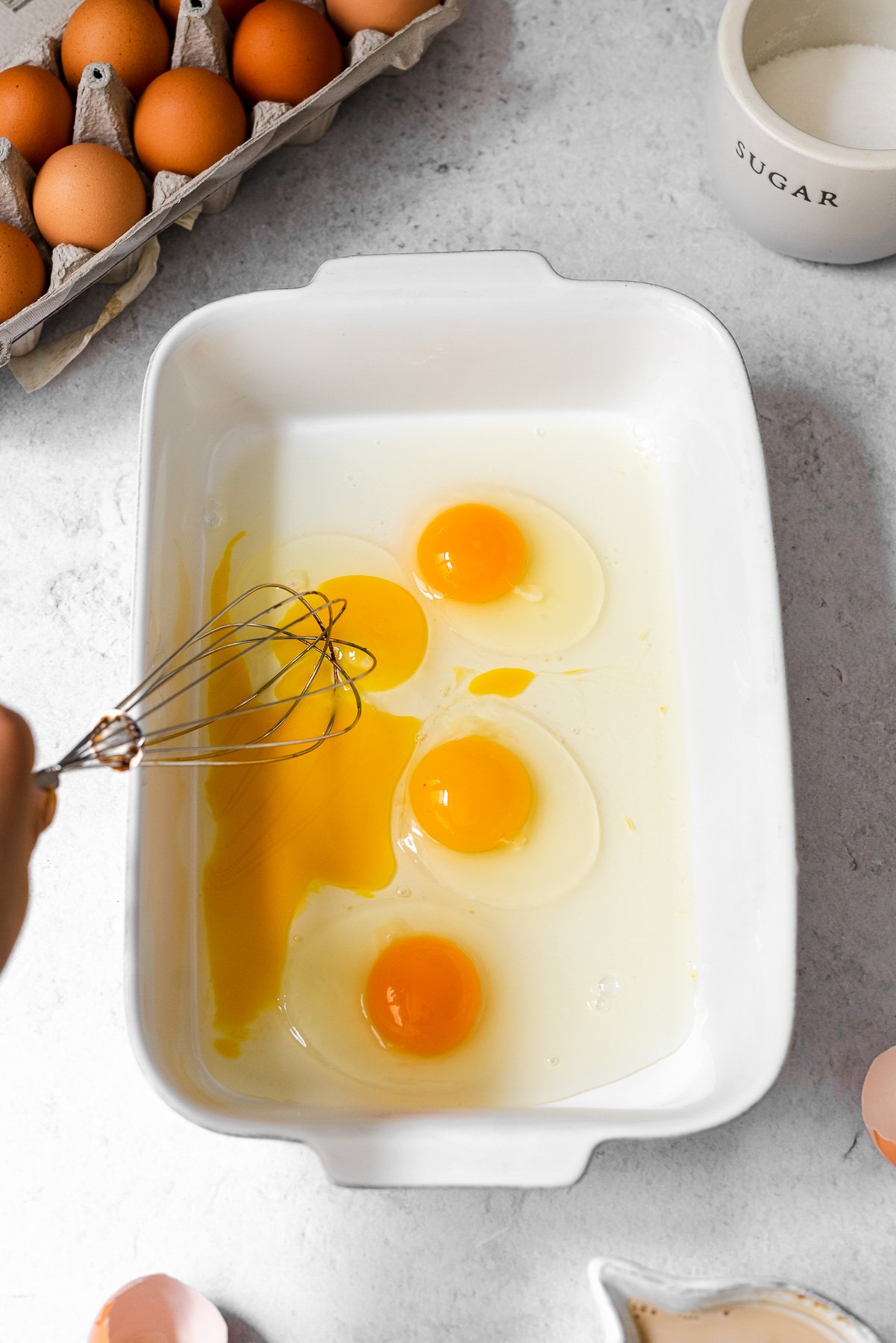 whisking eggs together in a large white baker