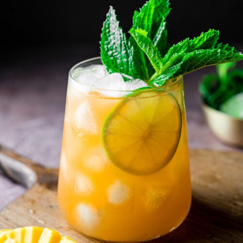mango iced tea in a glass with mint and a lime slice with a diced mango