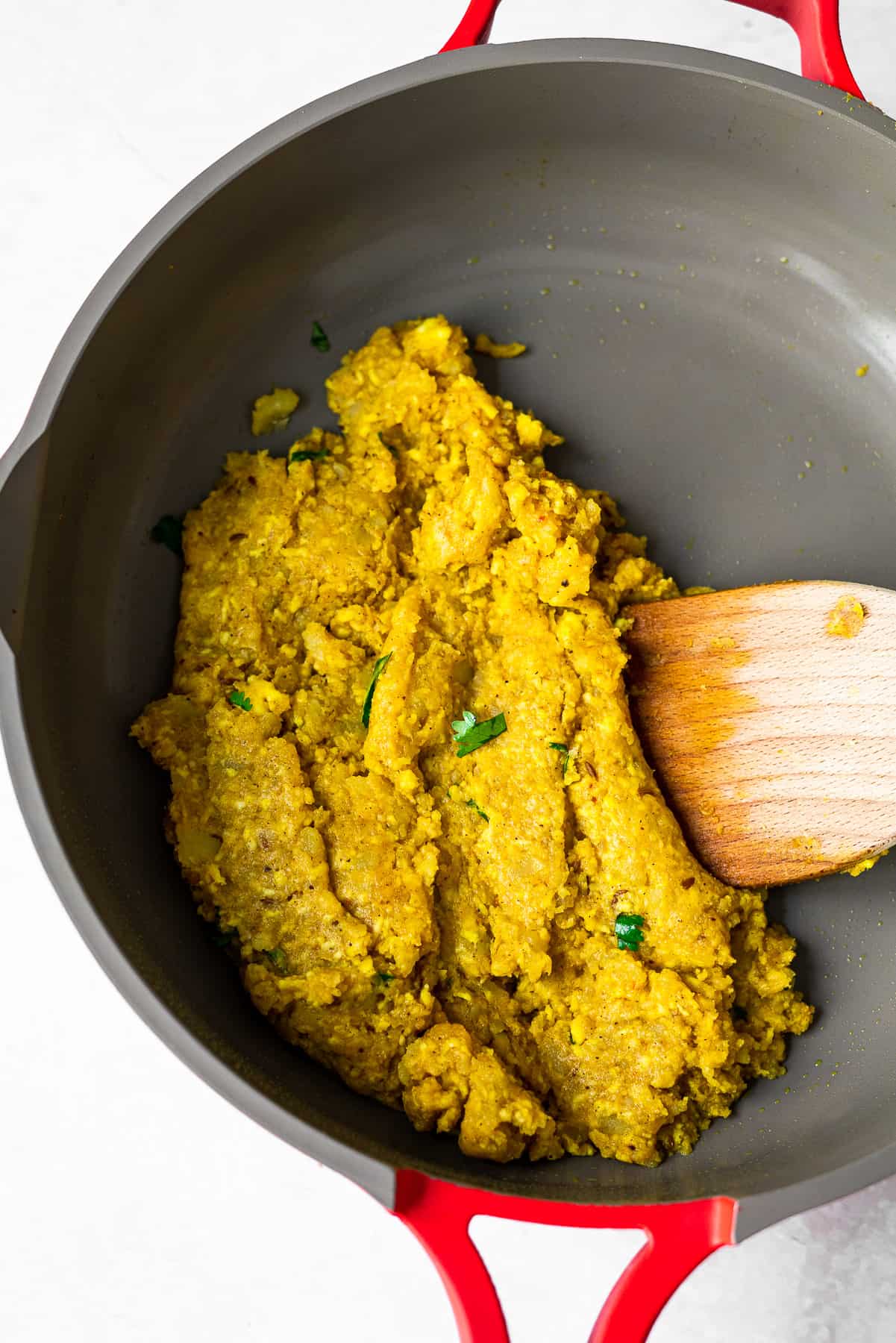 the paneer aloo filling of a samosa in a nonstick pan with a wooden spatula