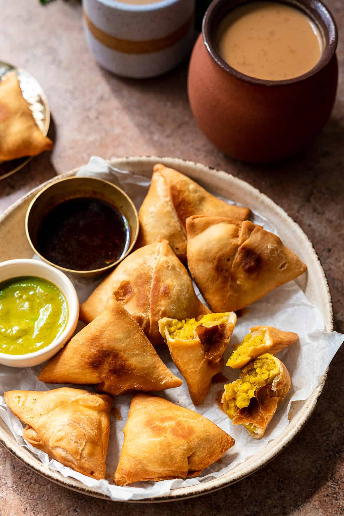 paneer aloo samosas in a bowl with chutneys and chai