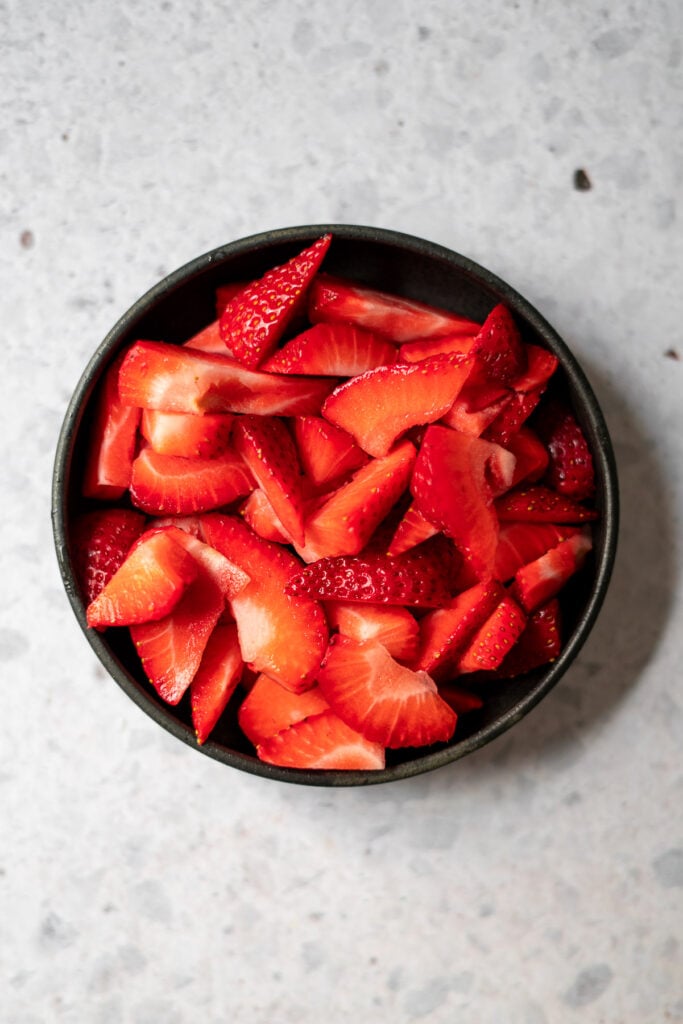 fresh sliced strawberries in a black bowl