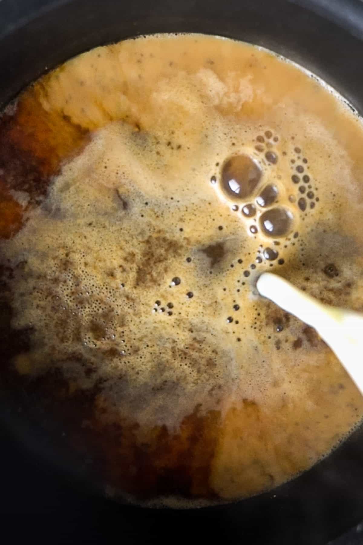 pouring milk into boiling chai in a pot