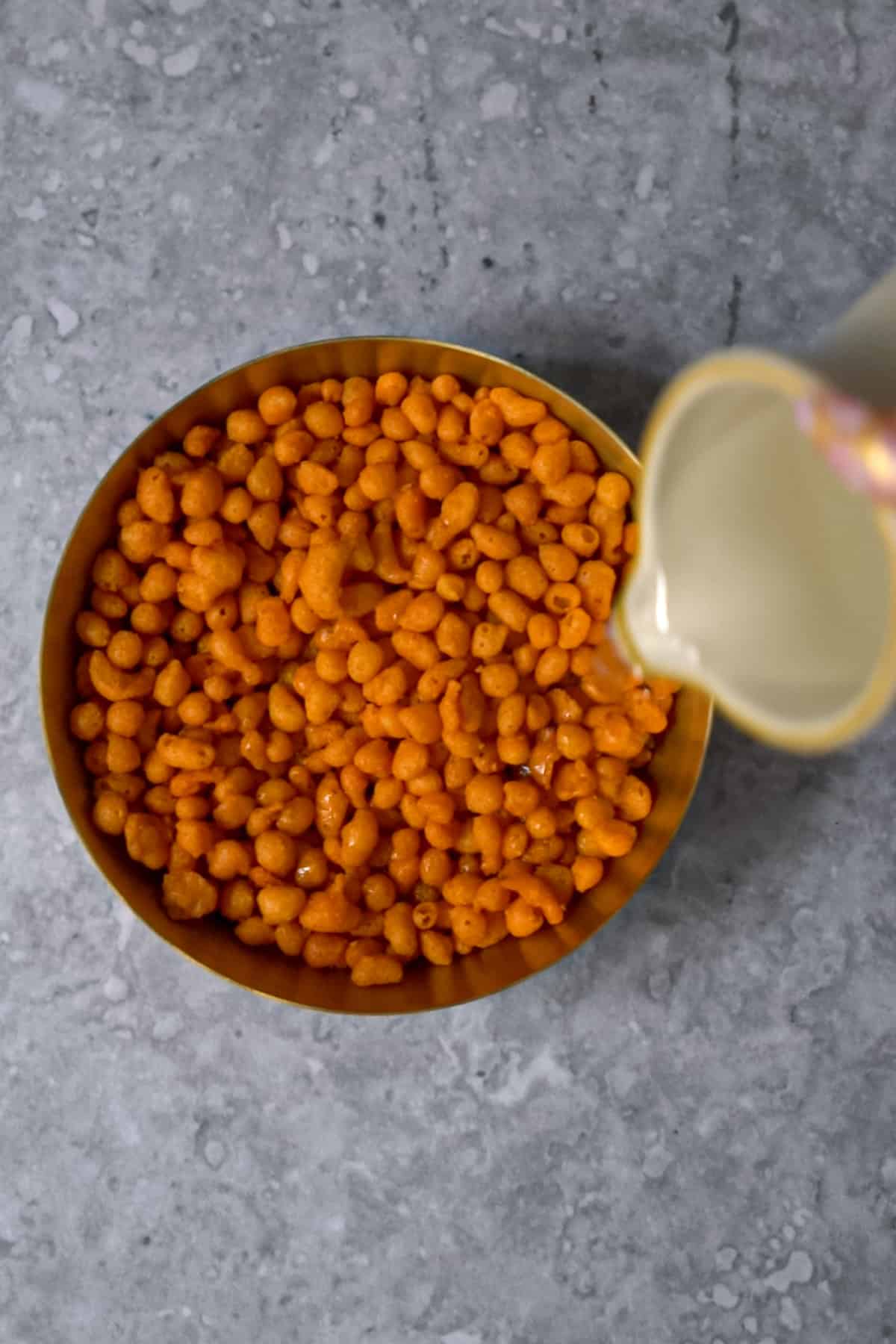 Pouring hot water into a bowl of boondi