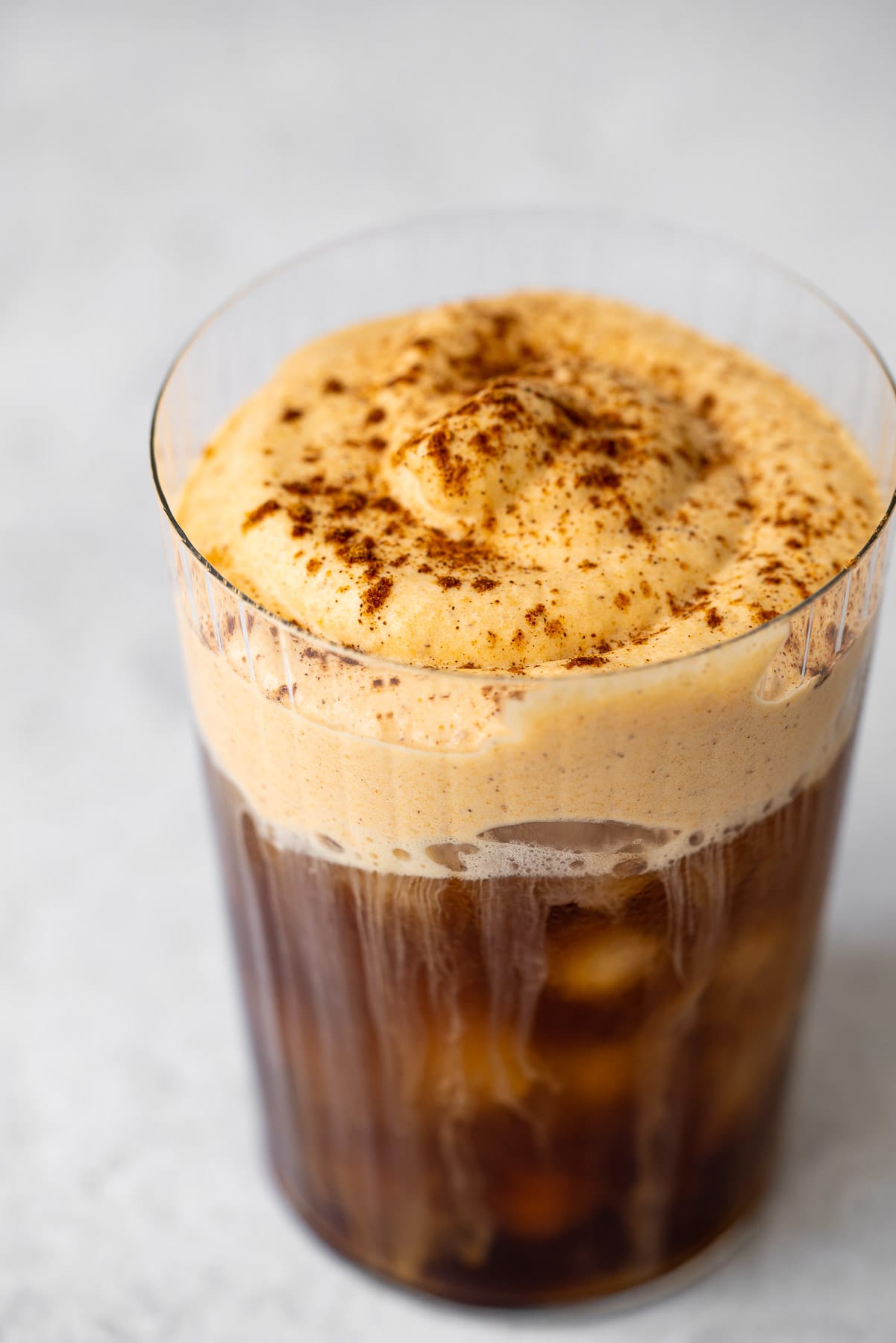 cup with iced coffee and pumpkin cream cold foam on top
