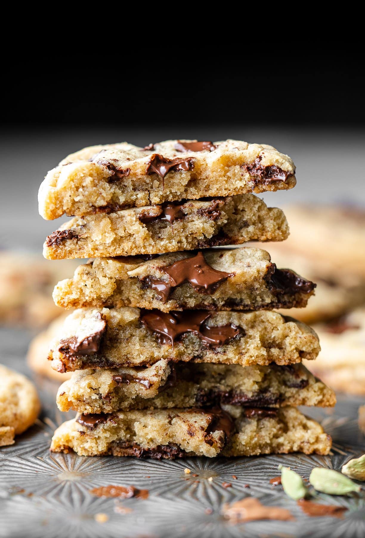 a stack of chai spice chocolate chip cookies broken in half on a baking sheet