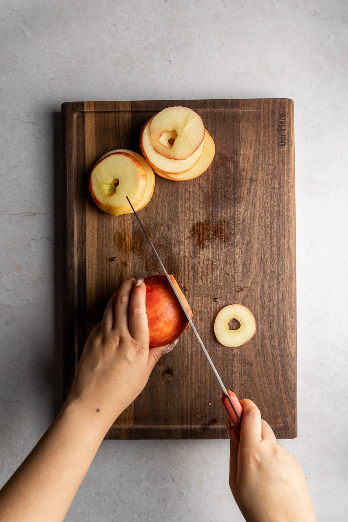 cutting honeycrisp apples into rings with a knife on a cutting board