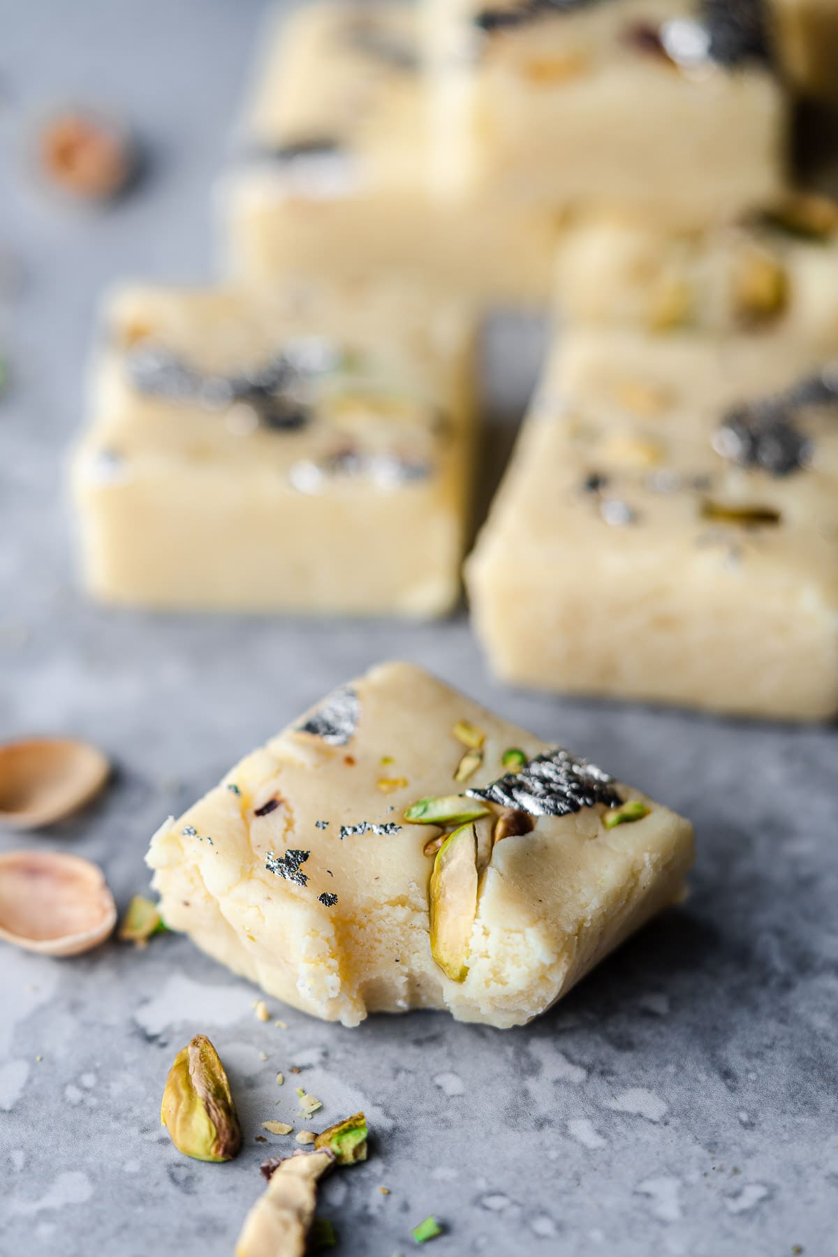 ein Bissen Milchpulver Barfi mit mehr Barfi im Hintergrund