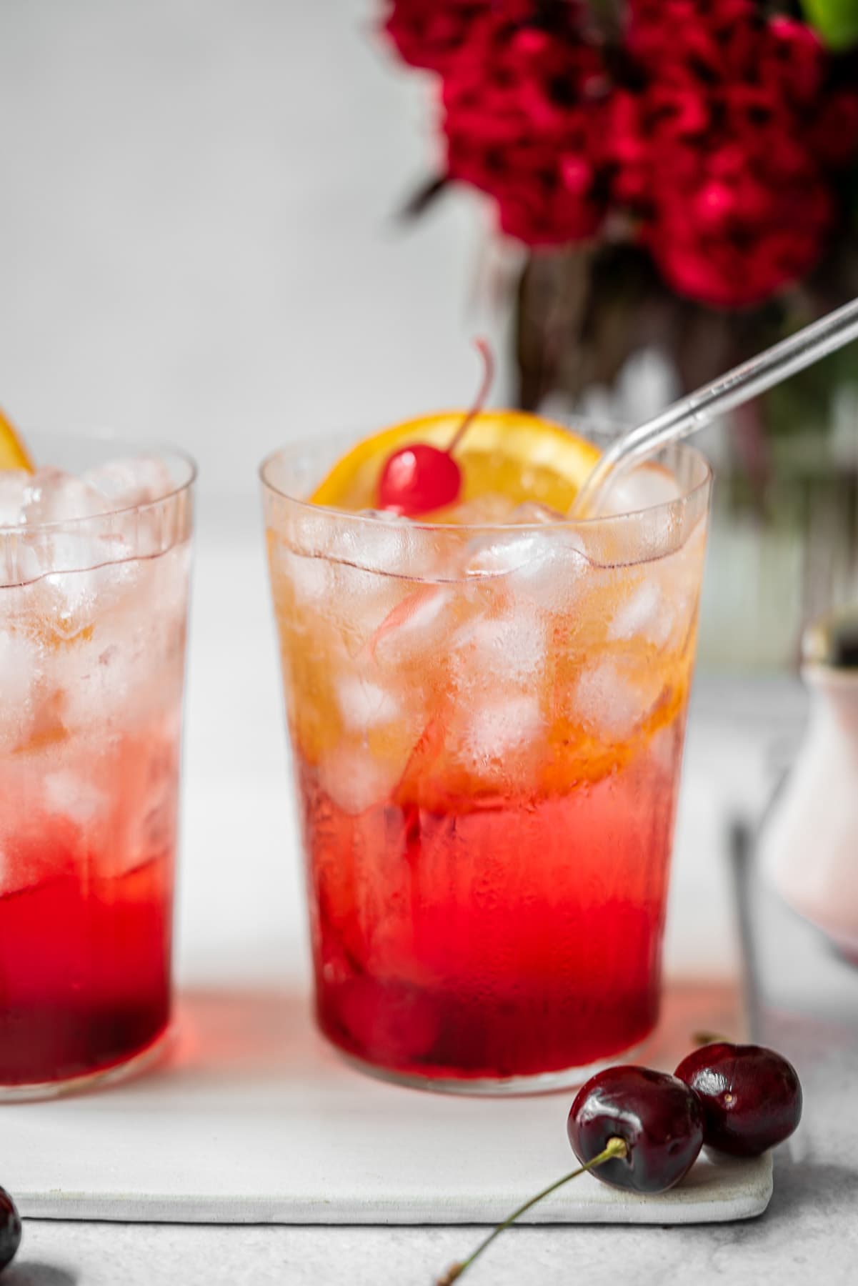 two glasses of shirley temple side by side with fresh cherries